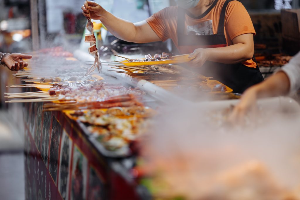 Large variety of delicious grilled seafood on wooden skewers. Street Food market with fresh meal for tourists. Traditional asian cuisine concept.